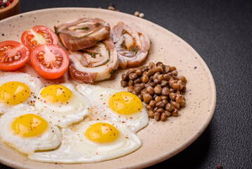 Delicious nutritious breakfast of fried quail eggs, bacon, legumes and cherry tomatoes