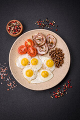 Fototapeta na wymiar Delicious nutritious breakfast of fried quail eggs, bacon, legumes and cherry tomatoes
