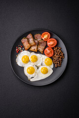 Delicious nutritious breakfast of fried quail eggs, bacon, legumes and cherry tomatoes