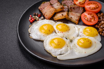 Delicious nutritious breakfast of fried quail eggs, bacon, legumes and cherry tomatoes