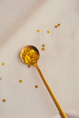 Spoon with golden stars confetti on white background. Festive concept