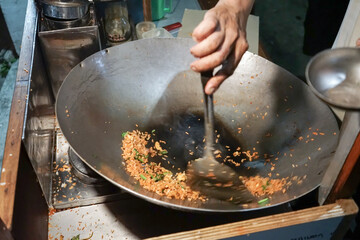A man cooking fried rice on steel skillet pan for selling on the street food. Indonesian call the...