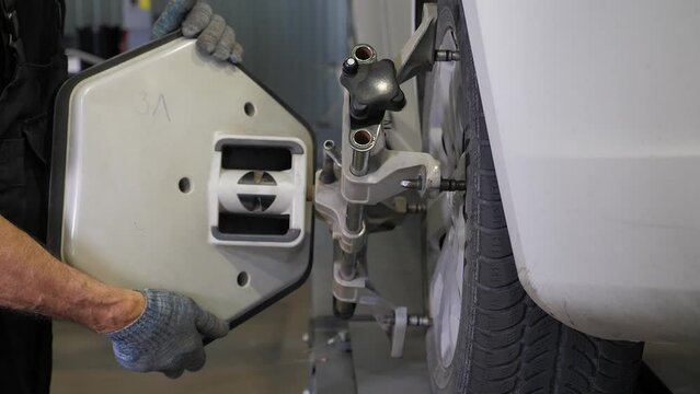 Balancing wheels on the car to the service station. A car service employee installs a wheel adapter with a target on the wheel to perform a wheel alignment. 