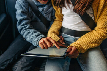 High angle view of girl using tablet PC with sister sitting in car