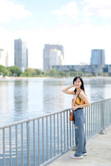 A positive expression in nature's embrace cute girl in an orange shirt stands on a bridge overlooking the water.