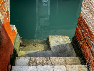 View of the steps for parking gondolas and boats leading into the water of the canal - obrazy, fototapety, plakaty