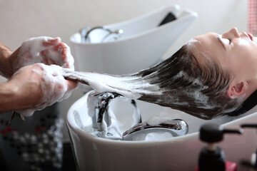 Woman washes her hair with shampoo in spa salon. Hairdressing services.Hairdresser at work. Concept...