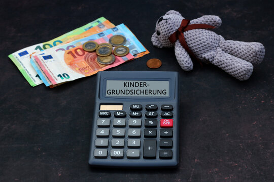 Kindergrundsicherung: Teddyb&auml;r mit Euro Banknoten, Taschenrechner und dem Text Kindergrundsicherung auf dem Display eines Taschenrechners.
