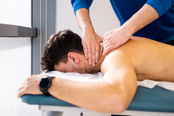 An unrecognizable physiotherapist massages a man's neck inside a clinic. Decontracting massage....
