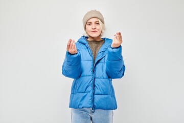 Young woman in blue winter jacket holding something in hand, demonstrating empty space for product...