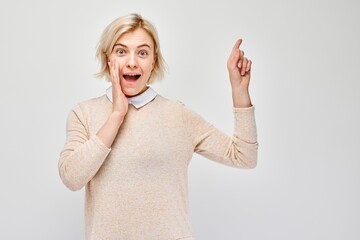 Young blond woman in casual pointing aside finger, demonstrating empty space for product or text...