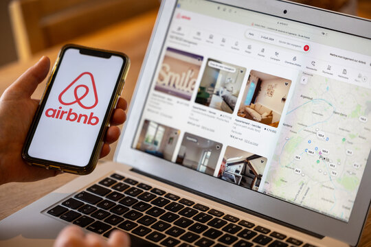 Paris,  France - November 30, 2023 : Female hand holding smartphone with Airbnb application. Airbnb is an online marketplace and hospitality service, enabling people  rent short-term lodging