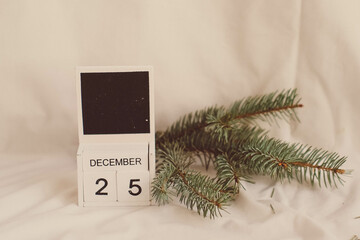 Wooden calendar for December 25 on the background of a Christmas tree.