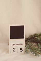 Wooden calendar for December 25 on the background of a Christmas tree.