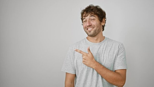 Cheerful young man in t-shirt, happily pointing and dubbing the isolated space by his side a natural expression on his smile filled face. adorable guy on a white background!
