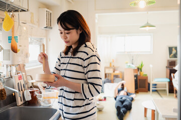 妻がお弁当を作っている後ろで寝転ぶ夫