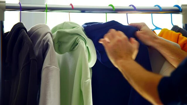 man choosing shirt on wardrobe hanger
