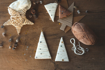 Christmas craft background with handmade yarn cone xmas trees in natural colors. DIY organic...