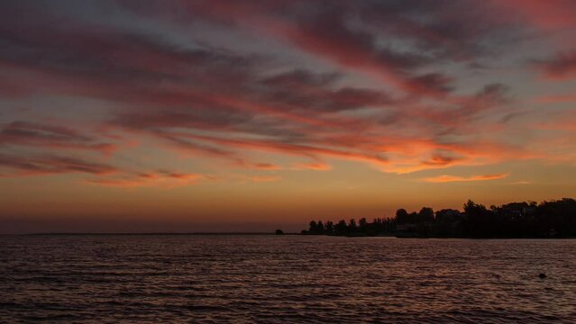 Clouds with a red sunset on a beautiful sky in the evening over the river, time lapse