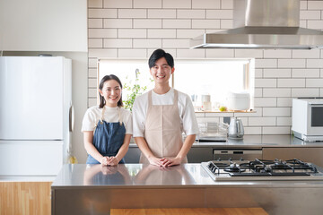 キッチンで料理する笑顔の夫婦 - obrazy, fototapety, plakaty