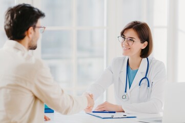 Doctor and patient shaking hands in a bright medical office, mutual respect