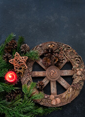 wiccan altar with Wheel of the year, candle, amulet deer, cones, fir branches on dark abstract...