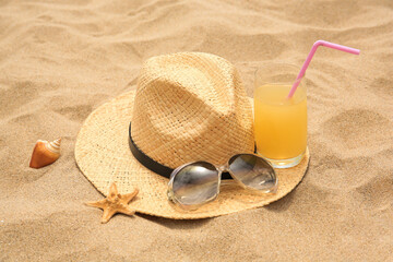 Fototapeta na wymiar Straw hat, sunglasses and refreshing drink on sand. Beach accessories
