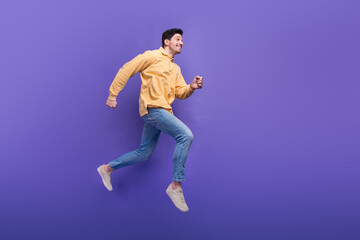 Fototapeta na wymiar Full length photo of handsome young guy running energetic have fun wear trendy yellow garment isolated on violet color background