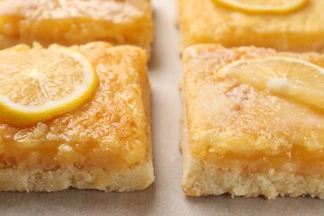 Tasty lemon bars on parchment paper, closeup