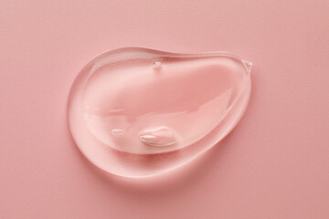 Smear of clear cosmetic gel on pink background, top view
