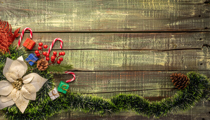Assorted Christmas decorations including a festive wreath, pine cones, and candy canes on an aged wooden surface. - Powered by Adobe