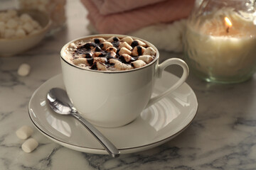 Cup of aromatic hot chocolate with marshmallows served on light marble table, closeup