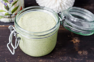 Homemade bentonite clay facial mask or body scrub in a glass jar. Natural beauty treatment and spa recipe.