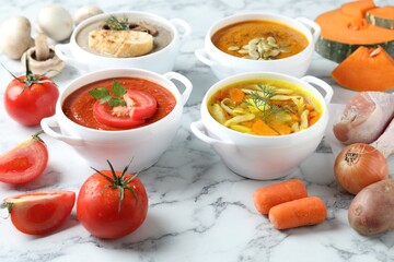Tasty broth, different cream soups in bowls and ingredients on white marble table, closeup