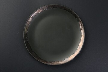 Beautiful ceramic plate on black background, top view