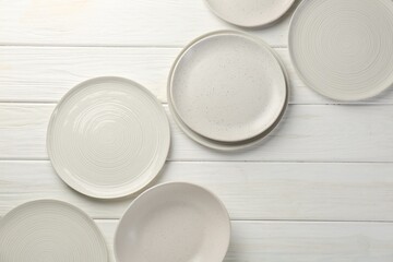 Beautiful ceramic plates on white wooden table, flat lay