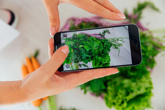 Woman taking pictures with her phone of vegetables for diet