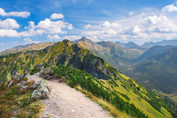 Polish Tatra Mountains, high mountain hiking trail leading to mountain peaks, mountain landscape with valleys and slopes, view on a sunny summer day. - obrazy, fototapety, plakaty