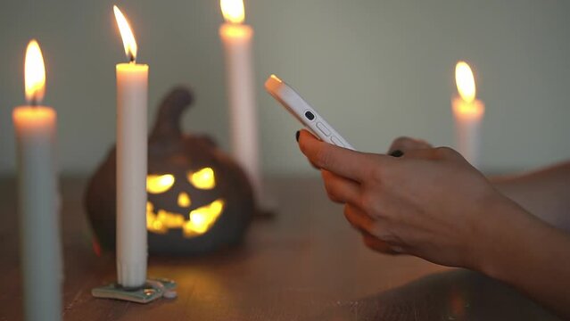 smartphone in a pink case in hand. Halloween pumpkin. close-up smartphone. slow-motion video. Record high quality video in Full HD format.
