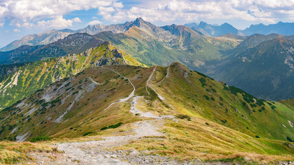 Polish Tatra Mountains, high mountain hiking trail leading to mountain peaks, mountain landscape with valleys and slopes, view on a sunny summer day.