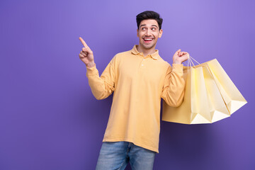 Photo portrait of handsome young guy point look empty space shopping wear trendy yellow garment isolated on violet color background