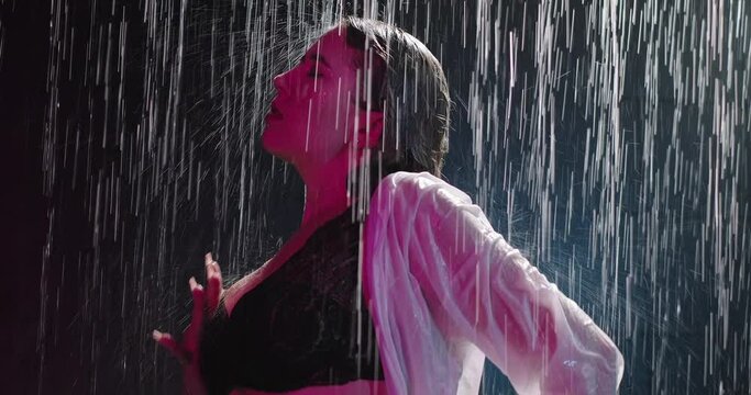 Wet woman moving her hand slowly across the body. Erotic woman in lingerie and shirt sits in the shower, water drops flow down the body. Provocative woman sensual moves. Slow motion