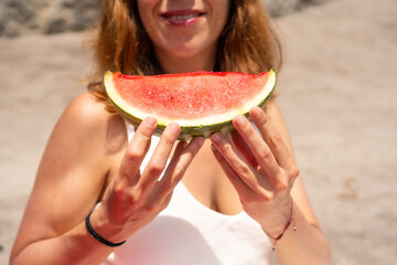 Close-up of a woman eating watermelon on the beach