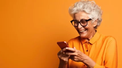 Foto op Plexiglas Happy senior woman waving on video call through smart phone against orange background © Olga