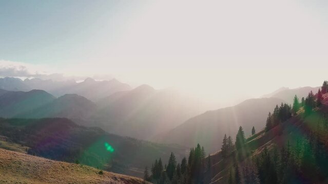 Drone footage of alpine mountain scenery with forests and mountains in the fall with setting sun. Backlit. Achensee, Tirol, Austria