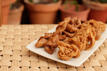 Moroccan chebakias on a white plate in a patio with plants