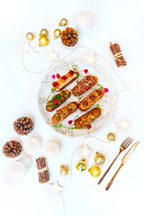 Eclairs on a marble plate on a background with Christmas or New Year decor