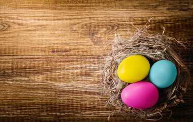 three eggs in a nest on a wooden surface, space for text