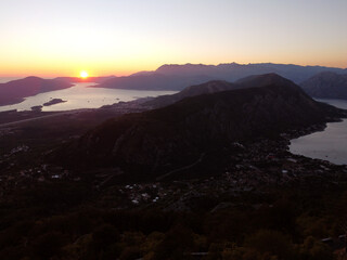 Aerial drone view of beautiful sunset or sunrise landscape with clear sky in the Bay of Kotor, Adriatic sea, Montenegro. Tranquil skyline with bright orange sunlight. Summer holiday concept