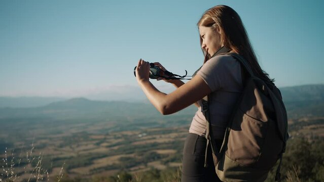 Young woman with backpack filming scenic landscape